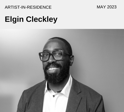Artist/Designer Elgin Cleckley - May 2023 - Black man wearing round glasses, sport coat and a white shirt. 